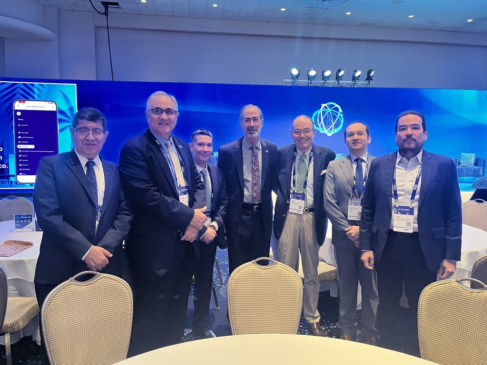 Nuestro CEO con otros asistentes frente al escenario de la 59.ª Asamblea Anual de FELABAN