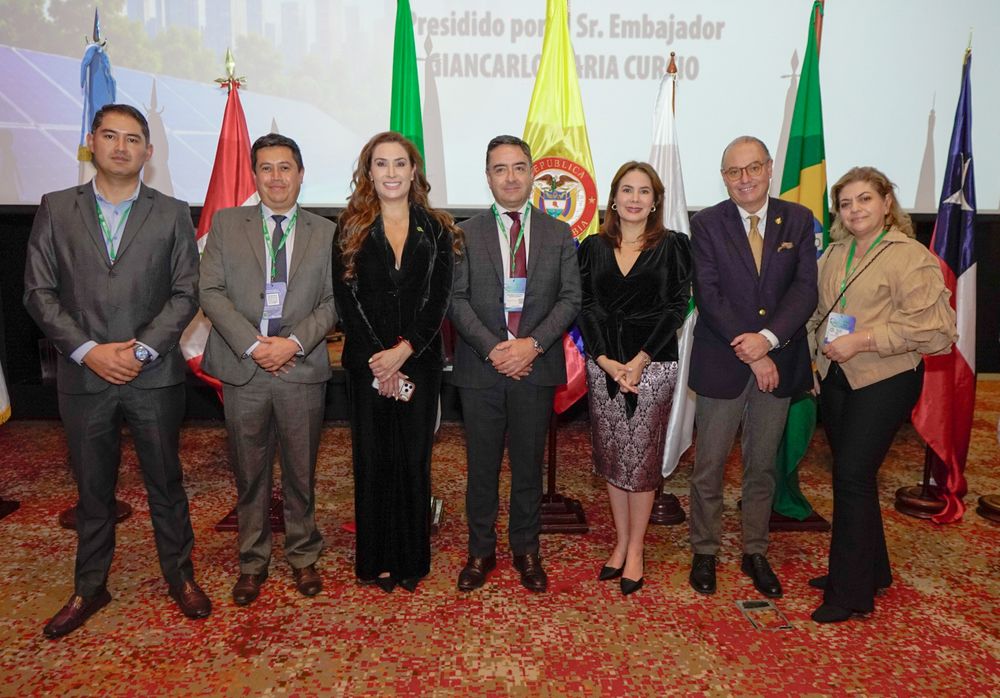 Foto de grupo de siete asistentes frente a banderas
