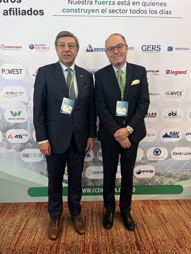 Dos asistentes con credenciales frente al panel de afiliados del congreso