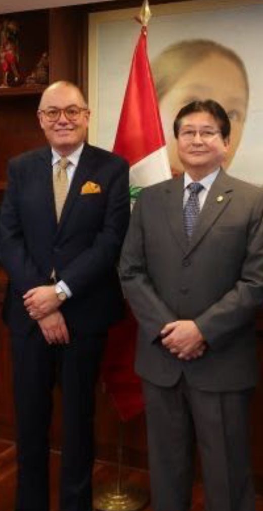 Dos participantes frente a la bandera del Perú