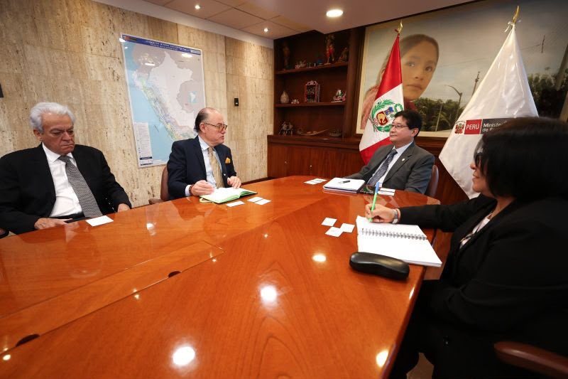 Reunión de trabajo en una sala con banderas del Perú y un mapa del país