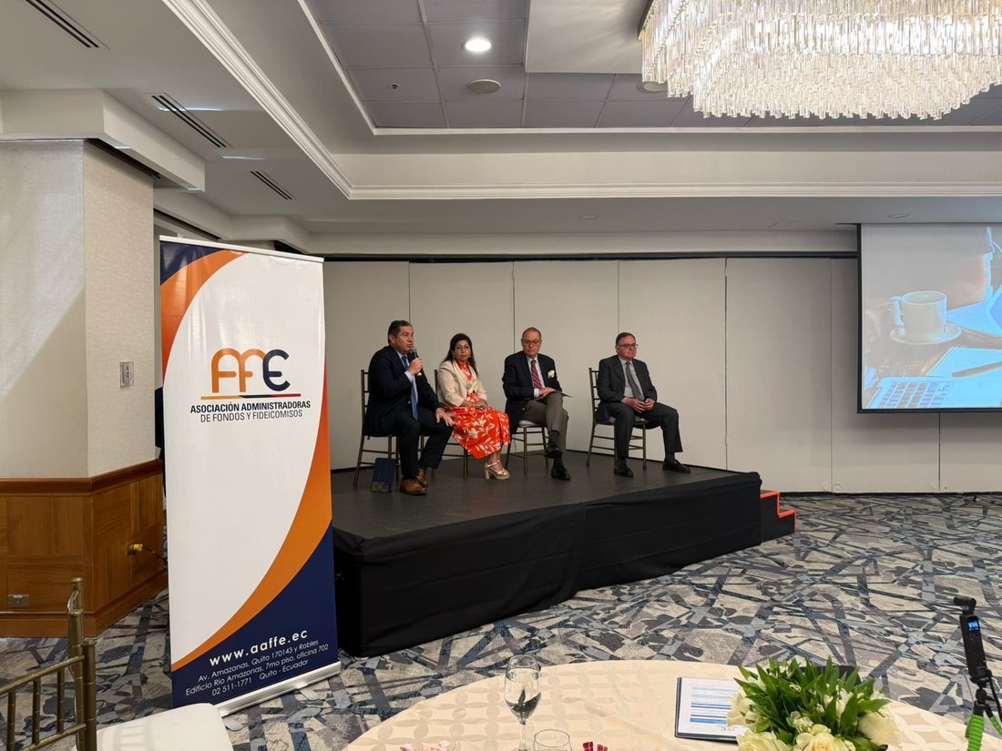 Panel en el escenario junto al roll-up de la Asociación de Administradoras de Fondos y Fideicomisos del Ecuador